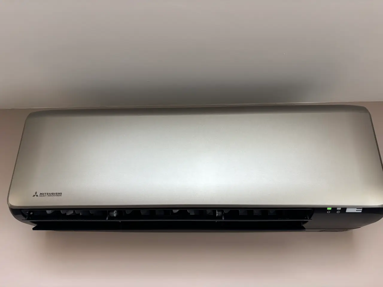 Een zilverkleurig wandmodel aan een witte muur, van dichtbij.