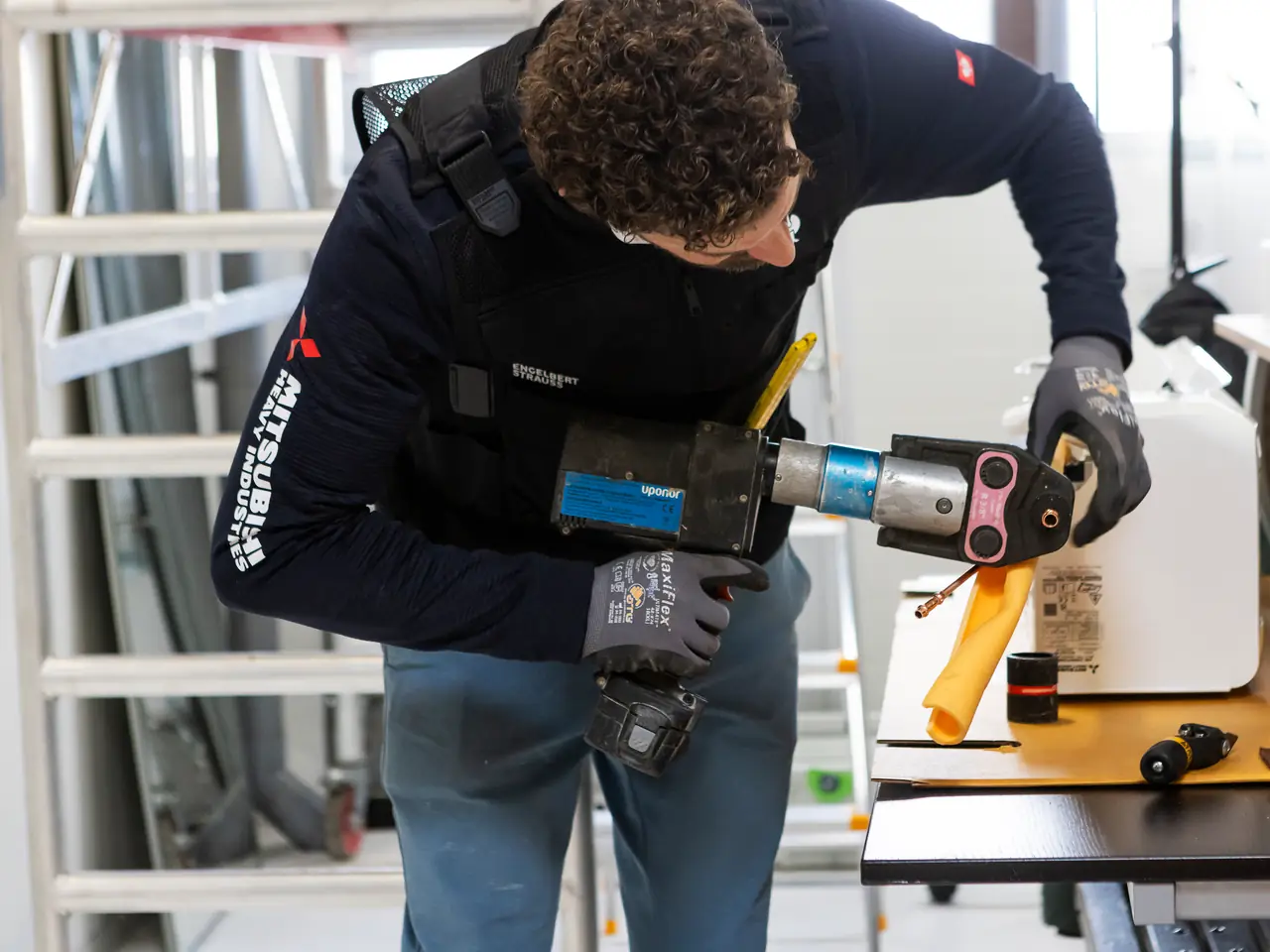 Rein perst aan de werkbank de koperen leiding van een nieuwe binnenunit vast.