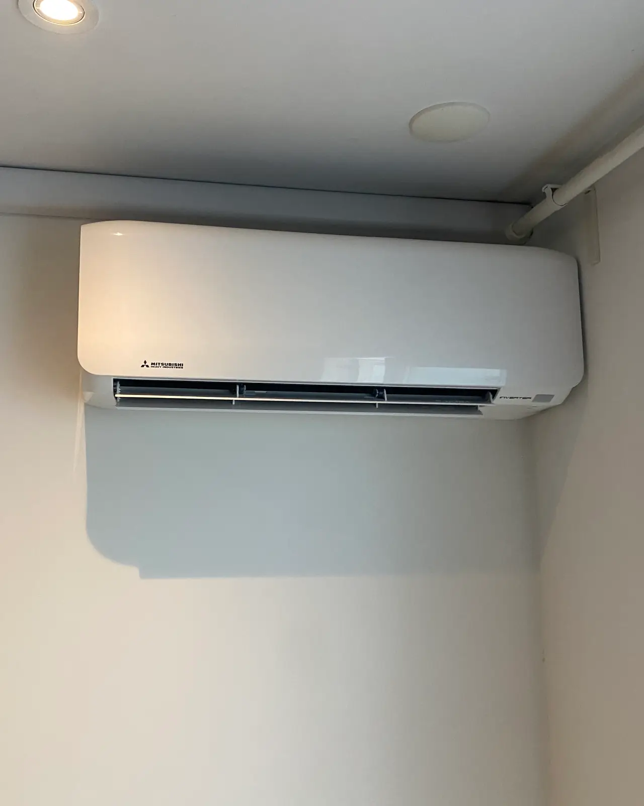 Een nieuw wit wandmodel strak onder het plafond, met de leiding in een witte goot naar de hoek.