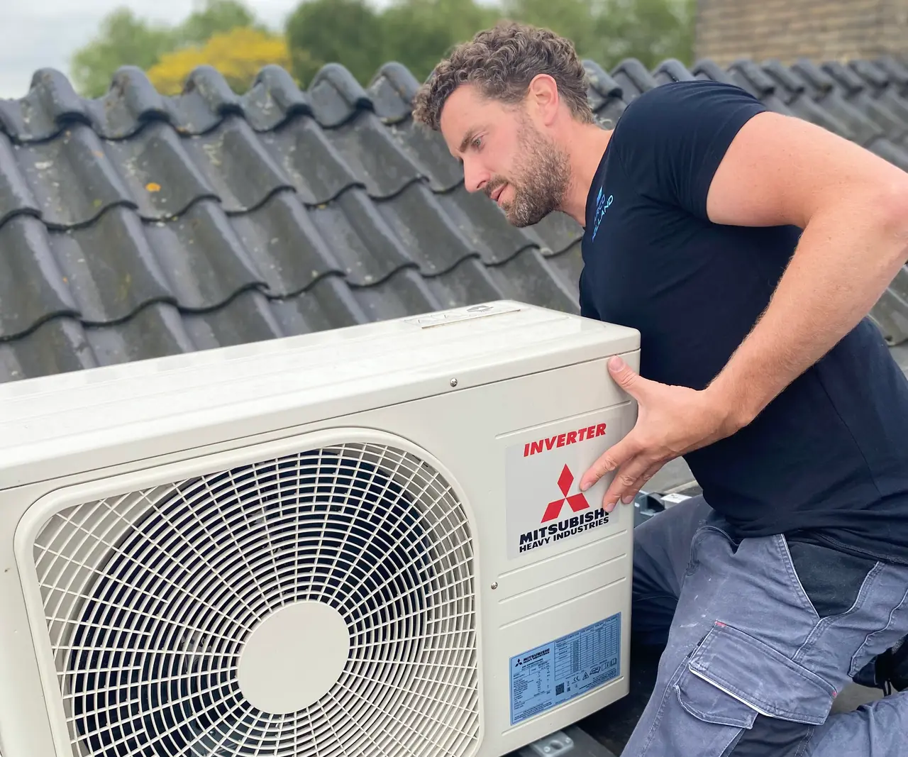 Rein tilt een nieuwe buitenunit van Mitsubishi Heavy Industries op de dragers op een pannendak.