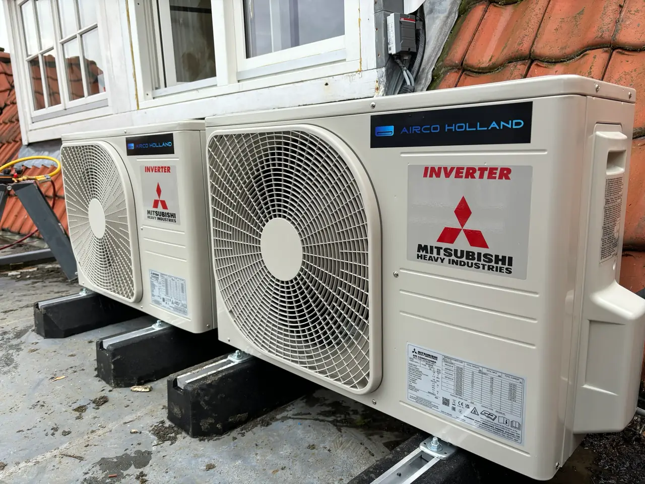Twee buitenunits met de stickers van Airco Holland en Mitsubishi Heavy Industries naast elkaar.
