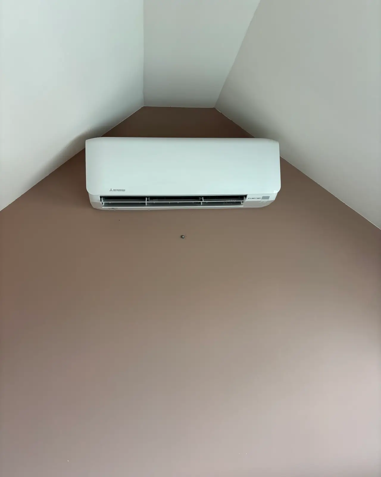 Een wit wandmodel hoog in de punt van een rustige zolderkamer, zonder leiding in beeld.