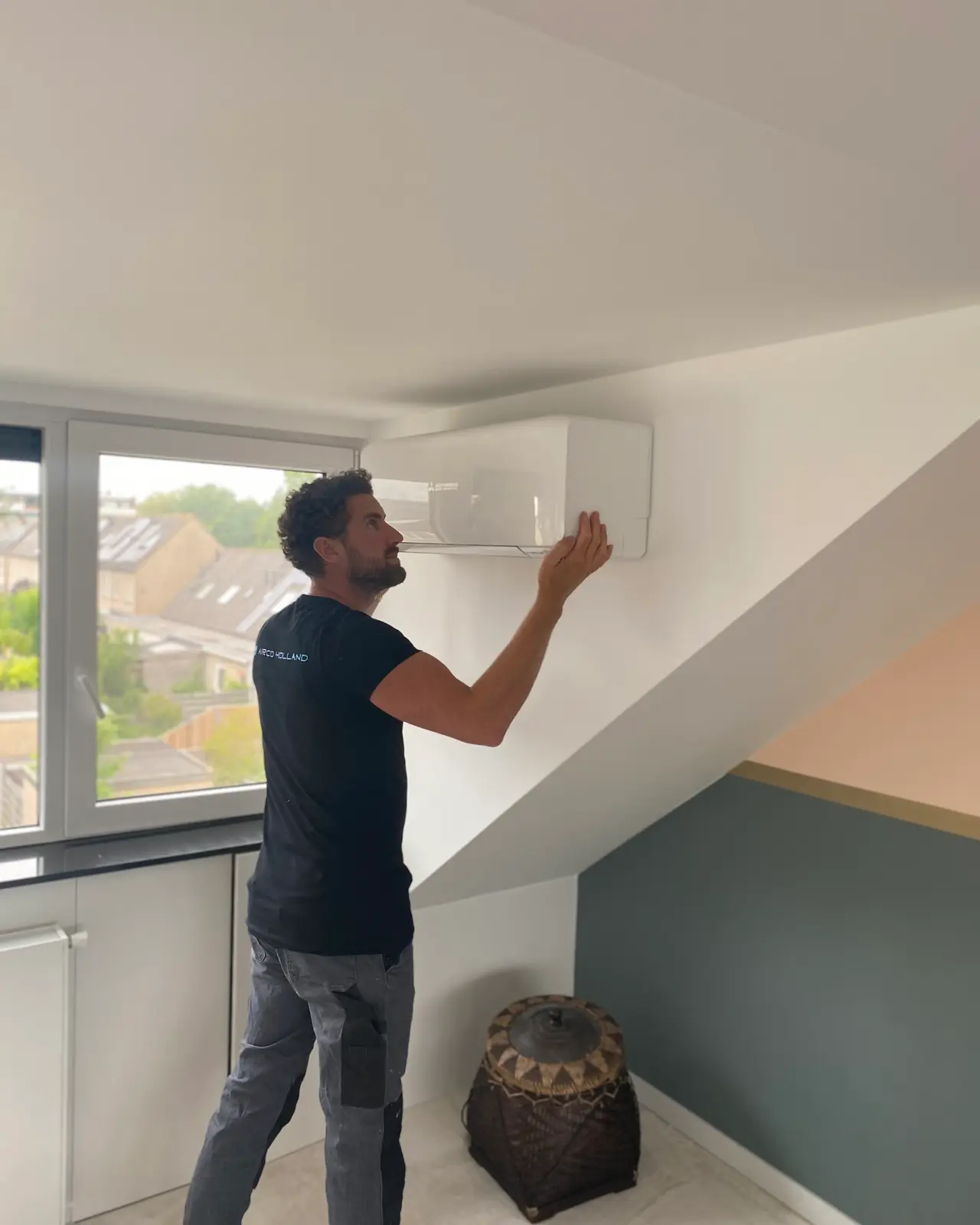 Rein stelt de lamel van een wit wandmodel bij, onder het schuine dak van een zolderkamer.