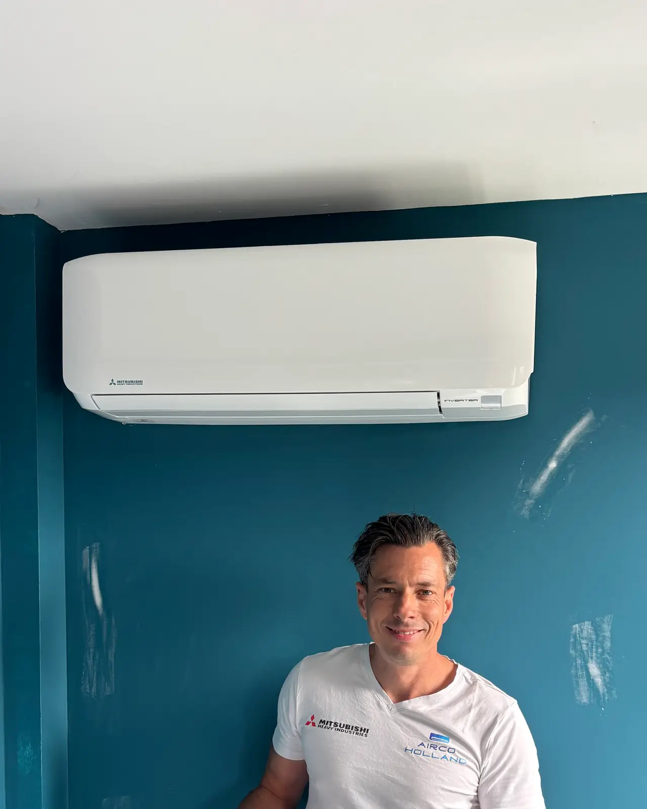 Een nieuw wit wandmodel aan een petrolblauwe muur, met Peter eronder.