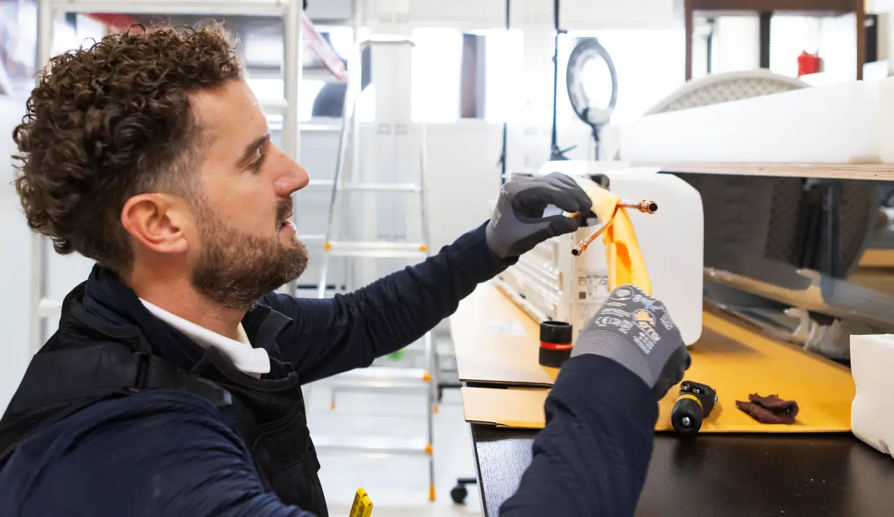 Rein at the workbench with the copper pipes of a new indoor unit, in yellow insulation.