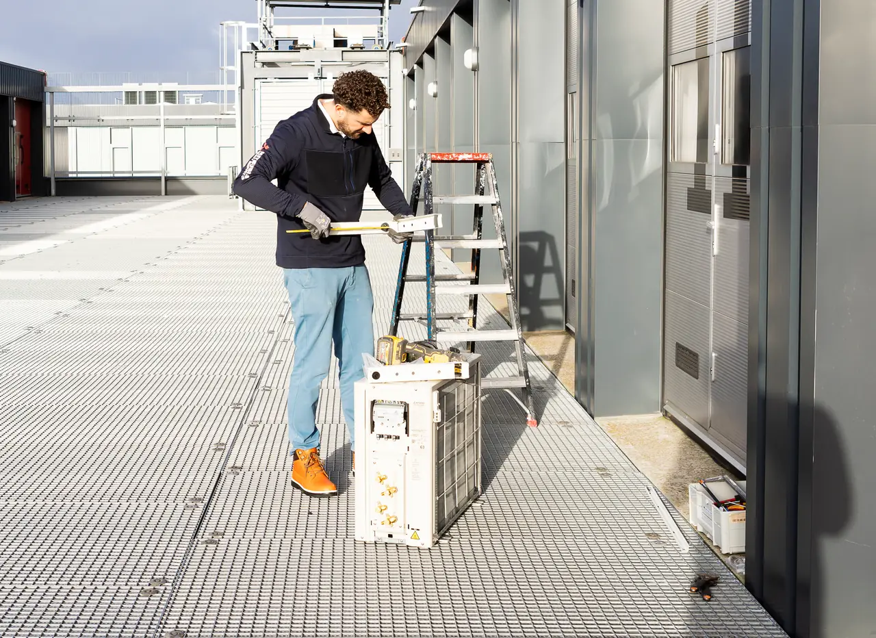 Rein aan het werk naast een nieuwe buitenunit op de galerij van een bedrijfsverzamelgebouw.